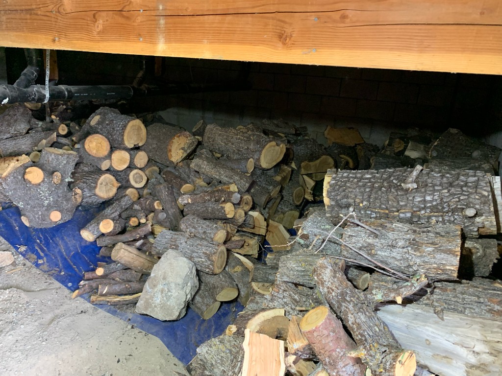 Firewood and logs stacked on a tarp in a basement storage area